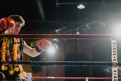 A Muay Thai fighter wearing red gloves in the ring.