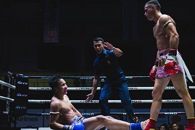 One Muay Thai fighter stands over another after a knock down.