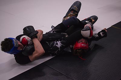 Two MMA fighters sparring on the mats working submission holds.