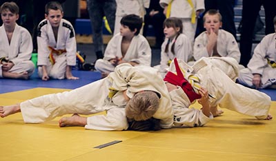 A Judo fighter attempts a submission choke in their sparring.