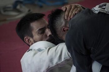 A BJJ player sinks in a choke hold on his opponent.