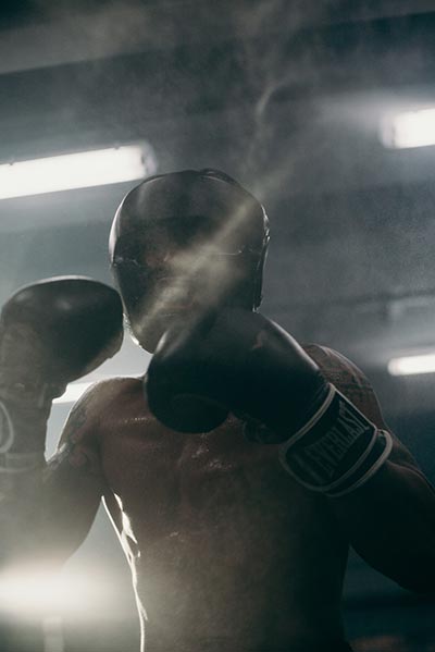 A boxer wearing protective headgear during a sparring session in the gym.