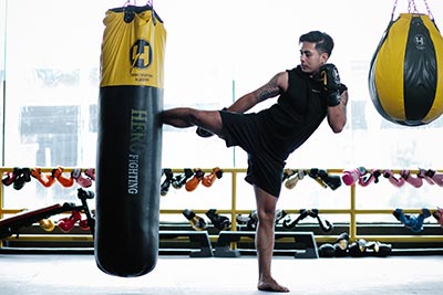 A fighter kicks the heavy bag during training.