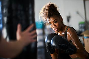 A black boxer in the gym with her coach.